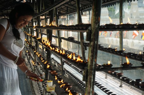 2 days in Kandy Central Province of Sri Lanka - Temple of the Sacred Tooth Relic - Sri Dalada Maligawa - religious young woman lighting a candle for her wishes to become true